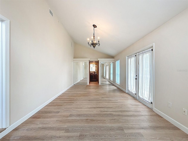 unfurnished dining area with lofted ceiling, a notable chandelier, light wood-style flooring, and visible vents