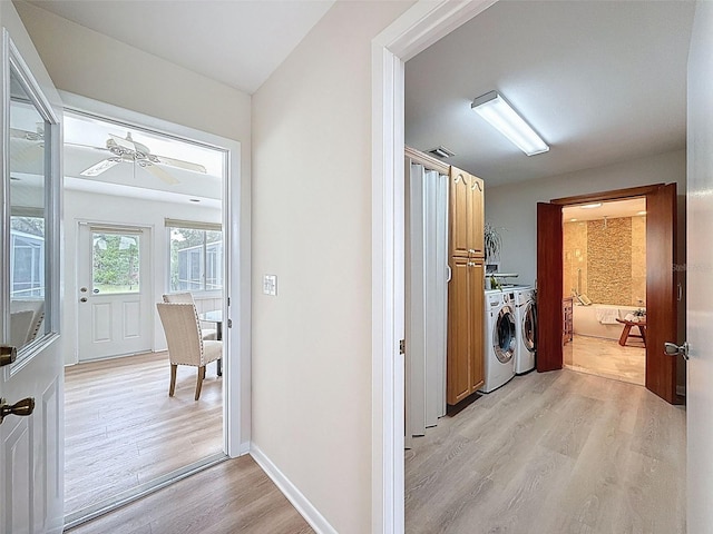 washroom with washing machine and dryer, light wood-type flooring, visible vents, and baseboards