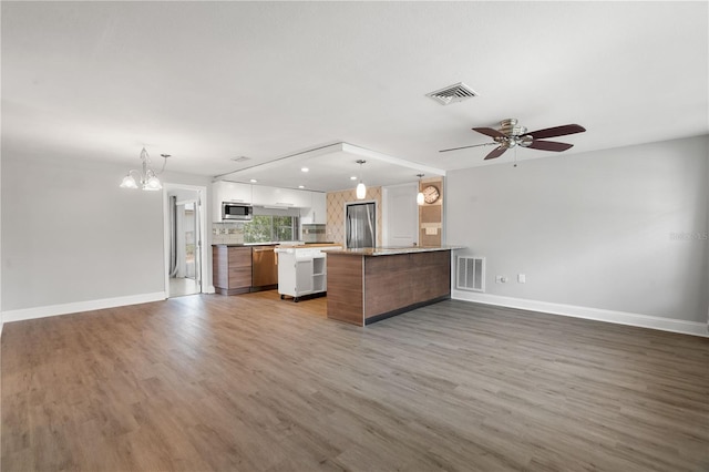 kitchen featuring appliances with stainless steel finishes, open floor plan, a chandelier, light countertops, and baseboards