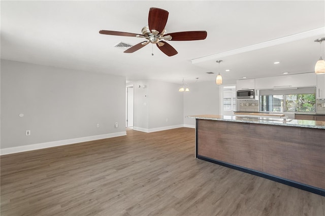 unfurnished living room featuring ceiling fan, wood finished floors, baseboards, and recessed lighting