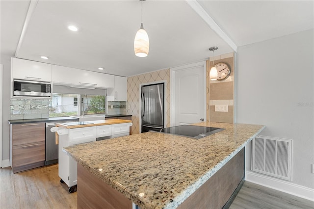 kitchen with appliances with stainless steel finishes, light wood-type flooring, a peninsula, baseboards, and white cabinetry
