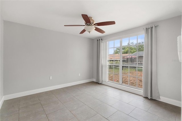 empty room with a ceiling fan, baseboards, and light tile patterned floors