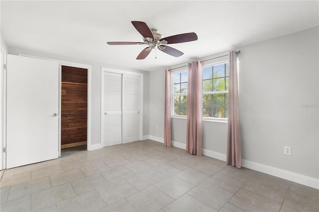 unfurnished bedroom with two closets, baseboards, and a ceiling fan