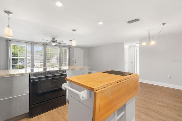 12407 Gunstock Ln, Hudson, FL 34667 - kitchen with light wood-type flooring, baseboards, butcher block counters, a chandelier, and a center island