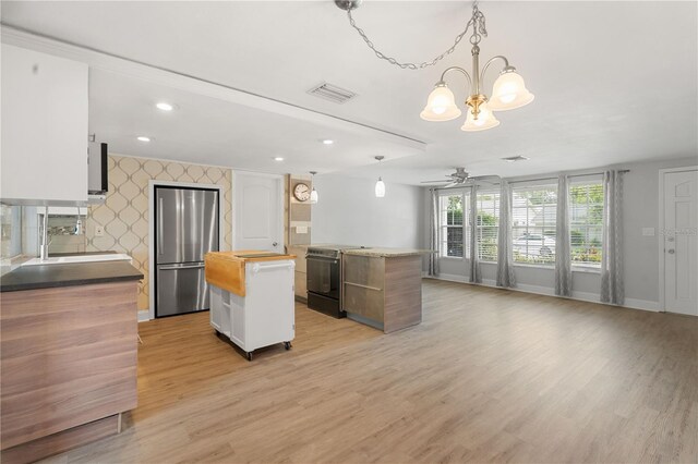 12407 Gunstock Ln, Hudson, FL 34667 - kitchen featuring freestanding refrigerator, range with electric stovetop, a kitchen island, butcher block counters, and light wood-style floors