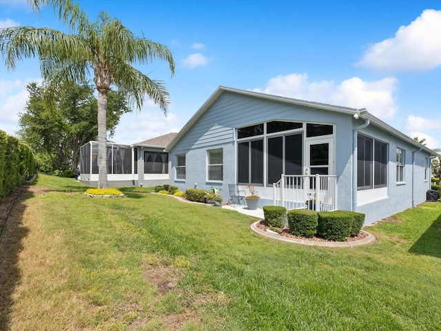 back of house featuring a sunroom and a lawn