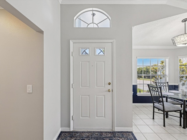 entrance foyer featuring light tile patterned flooring, baseboards, crown molding, and a textured ceiling