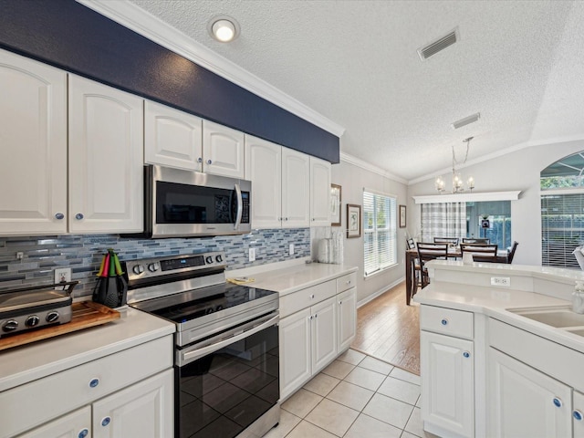 kitchen featuring appliances with stainless steel finishes, plenty of natural light, ornamental molding, light tile patterned floors, and a chandelier
