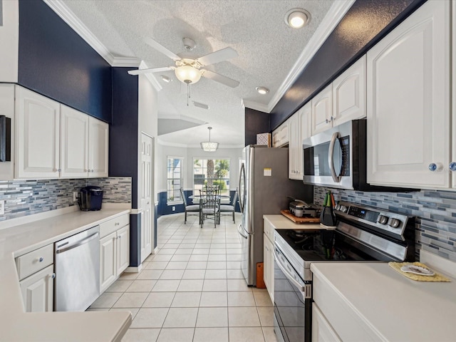 kitchen with stainless steel appliances, a textured ceiling, ornamental molding, light tile patterned floors, and white cabinets