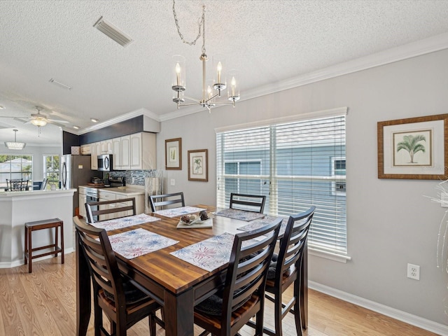 dining area featuring a textured ceiling, light wood-type flooring, a chandelier, crown molding, and a ceiling fan