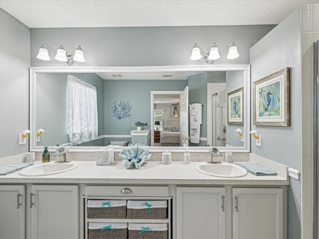 ensuite bathroom featuring a stall shower, double vanity, and a textured ceiling