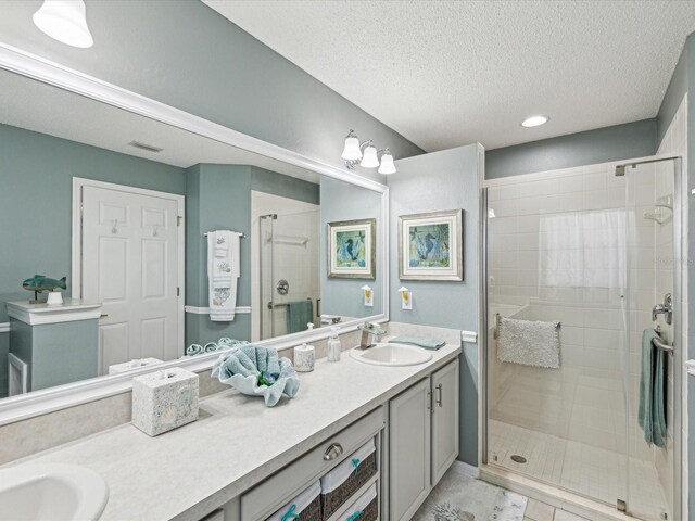 full bathroom with a shower stall, double vanity, a textured ceiling, recessed lighting, and tile patterned floors