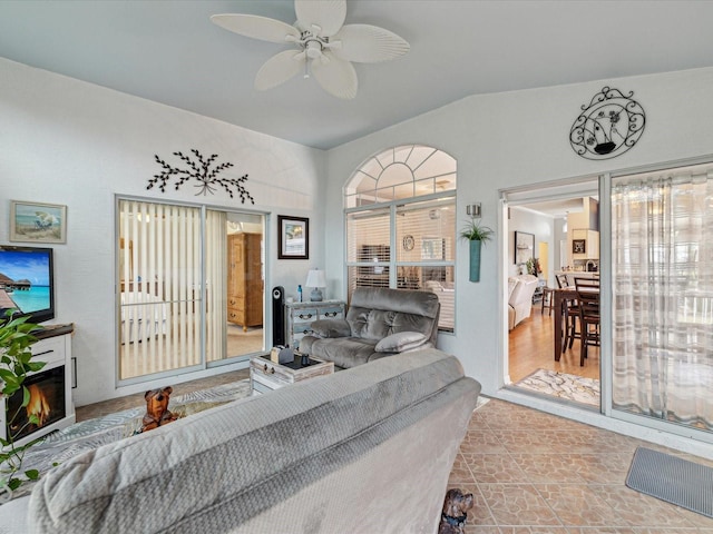living room with a glass covered fireplace and ceiling fan