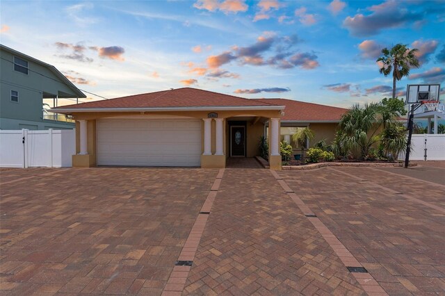 view of front of house featuring stucco siding, a garage, fence, decorative driveway, and a gate