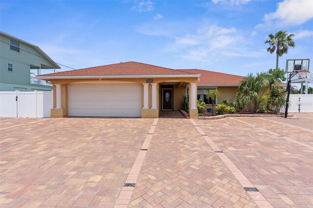 view of front of house with fence, stucco siding, a garage, decorative driveway, and a gate