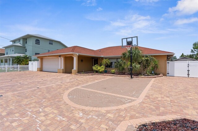 view of front of property featuring a gate, stucco siding, fence, and curved driveway