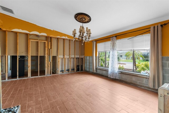 unfurnished room featuring a chandelier, ornamental molding, and wood finished floors