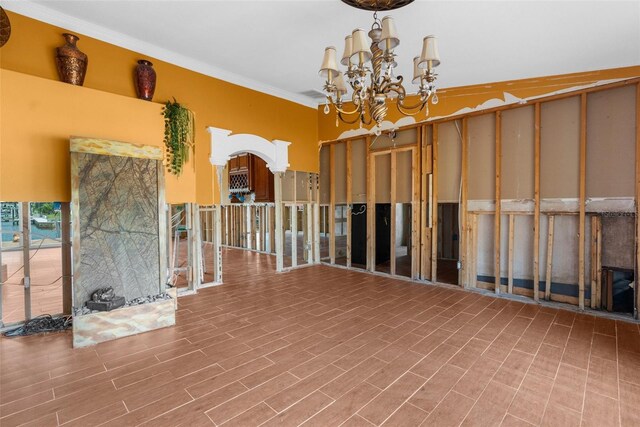 empty room featuring a chandelier, crown molding, and wood finished floors