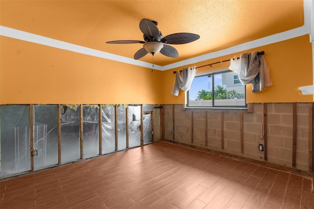 empty room with wainscoting, ornamental molding, a ceiling fan, and wood finished floors