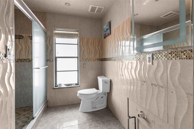 bathroom with plenty of natural light, toilet, a stall shower, and tile walls