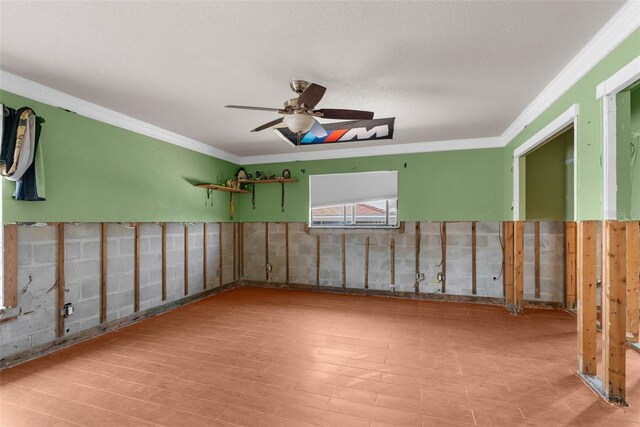 unfurnished room with a ceiling fan, ornamental molding, wood finished floors, and wainscoting