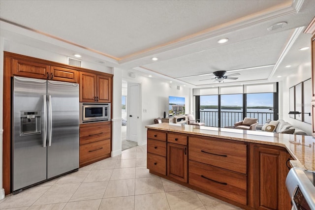4550 Bay Blvd Unit 1231, Port Richey, FL 34668 - kitchen featuring stainless steel appliances, brown cabinetry, light stone counters, a ceiling fan, and light tile patterned floors