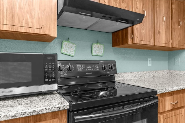 kitchen with stainless steel microwave, brown cabinets, under cabinet range hood, and electric range