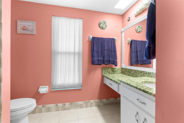 bathroom with vanity, toilet, a skylight, and tile patterned flooring