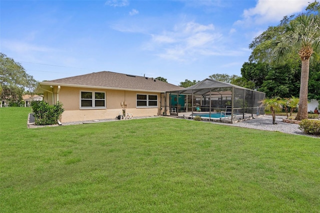 rear view of house with stucco siding, a lawn, an outdoor pool, and glass enclosure