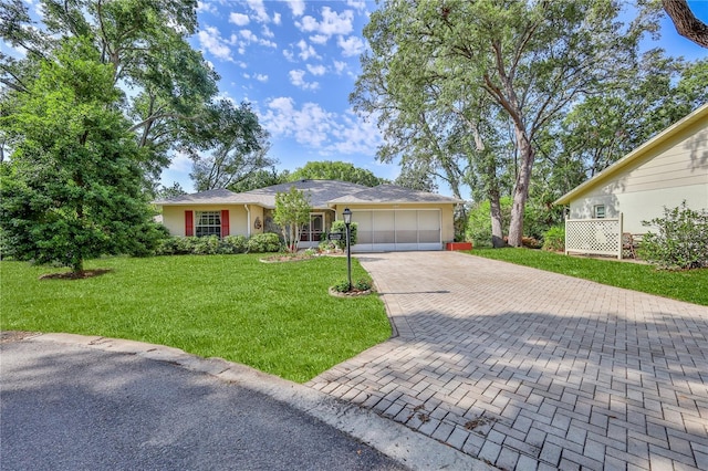 ranch-style home featuring stucco siding, a garage, a front lawn, and decorative driveway