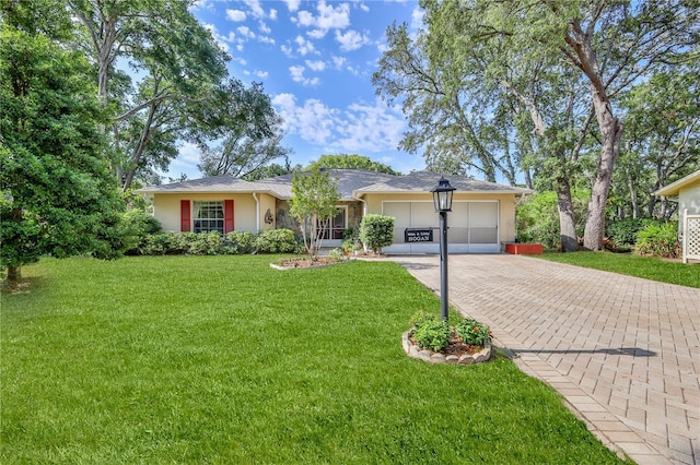 single story home with an attached garage, decorative driveway, stucco siding, and a front yard