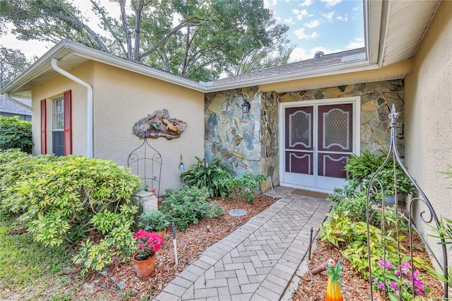 doorway to property featuring stucco siding and stone siding