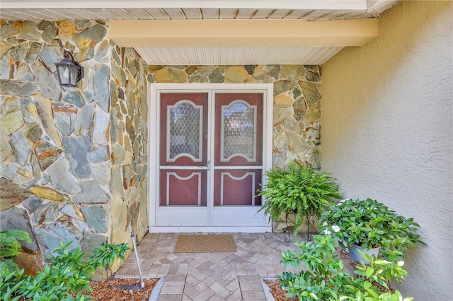 doorway to property featuring stone siding and stucco siding