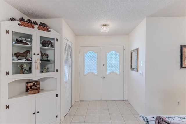 foyer featuring a textured ceiling, light tile patterned flooring, and french doors