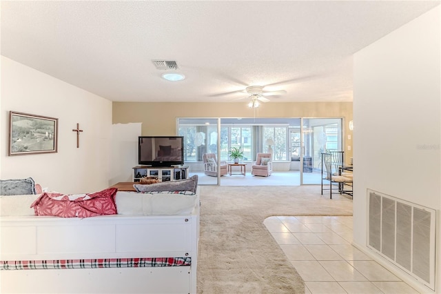 living area featuring ceiling fan, light carpet, a textured ceiling, and visible vents