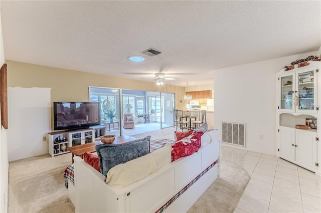living room with a textured ceiling, visible vents, and a ceiling fan