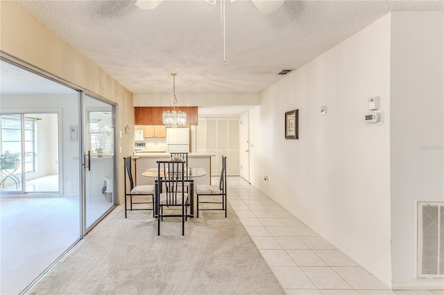 dining space with light colored carpet, a textured ceiling, light tile patterned floors, and visible vents