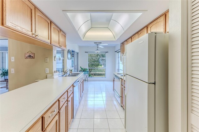 kitchen featuring light tile patterned floors, white appliances, a sink, a raised ceiling, and light countertops
