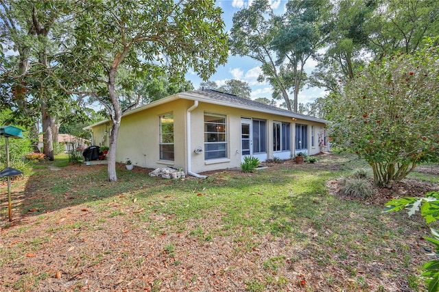 view of side of property with stucco siding and a lawn