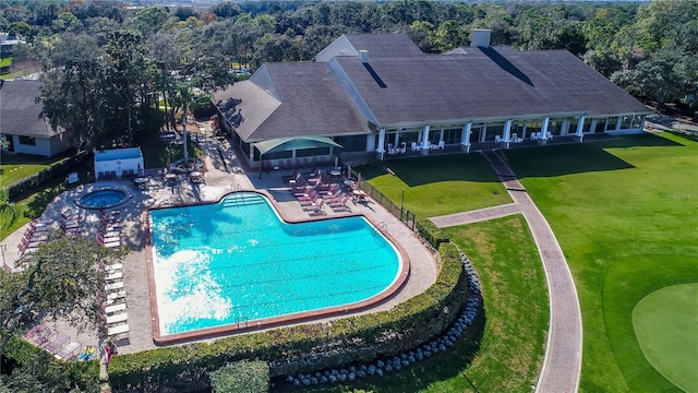 pool featuring a lawn, a patio area, a community hot tub, and fence
