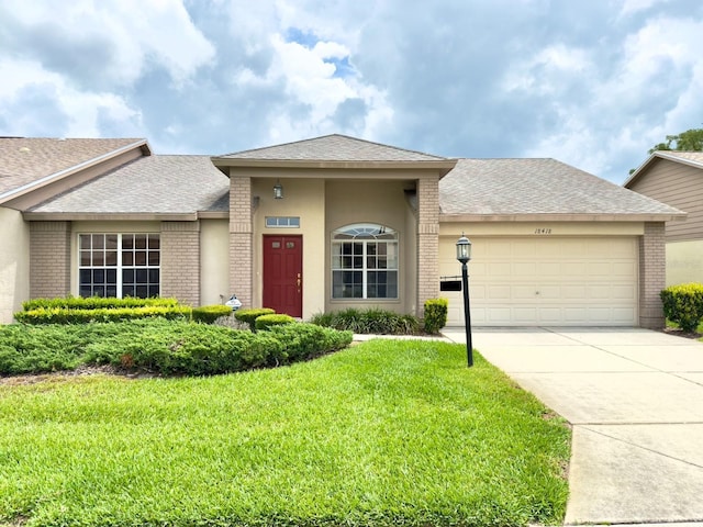 view of front facade with brick siding, an attached garage, a front lawn, concrete driveway, and a shingled roof