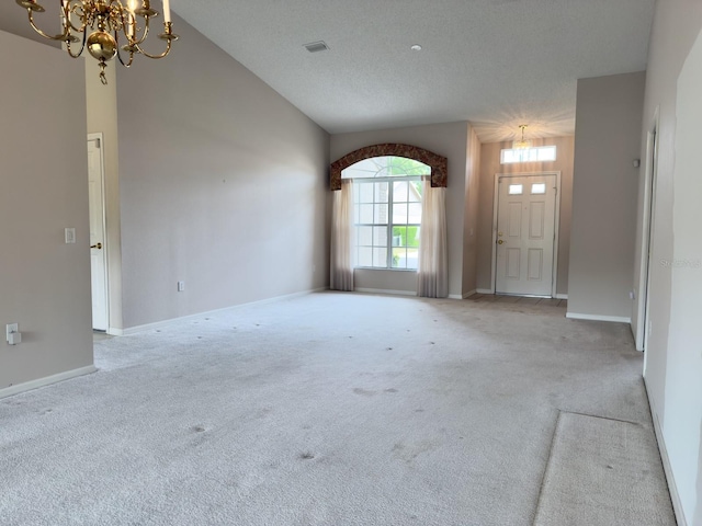 carpeted empty room with a chandelier, lofted ceiling, and baseboards