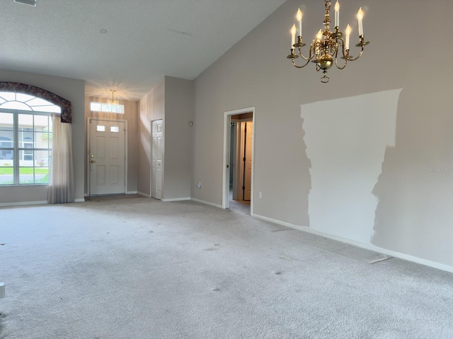 spare room featuring a chandelier, light colored carpet, baseboards, and high vaulted ceiling