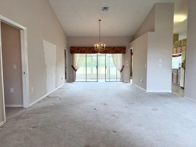 empty room with a chandelier, light carpet, vaulted ceiling, and baseboards