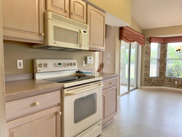 kitchen featuring white appliances, light countertops, vaulted ceiling, and light tile patterned floors