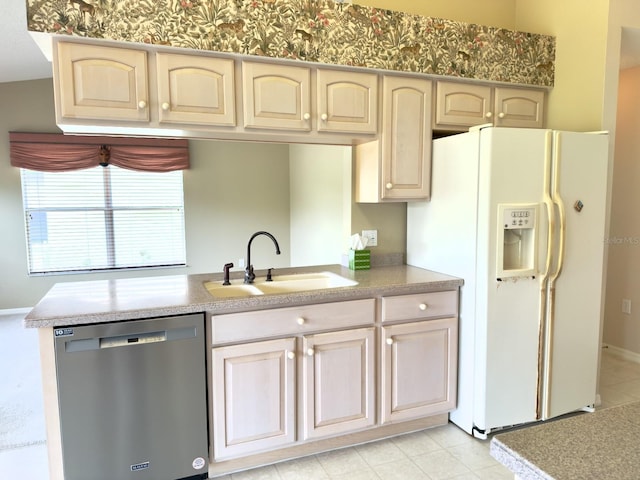 kitchen featuring stainless steel dishwasher, white fridge with ice dispenser, a sink, cream cabinets, and light countertops