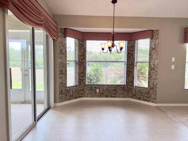 unfurnished dining area featuring a chandelier and baseboards