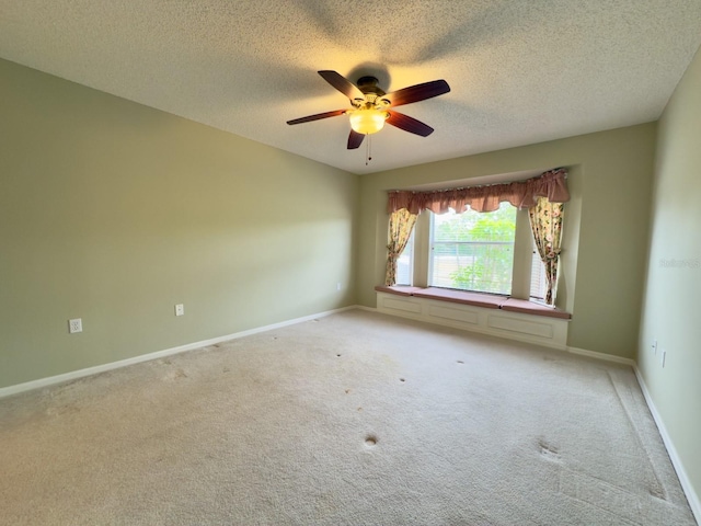 unfurnished room featuring a ceiling fan, light carpet, a textured ceiling, and baseboards