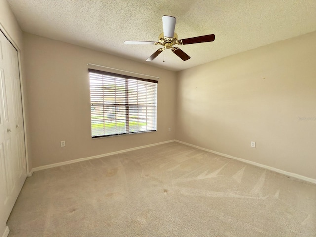 unfurnished bedroom featuring a closet, light colored carpet, baseboards, and a textured ceiling