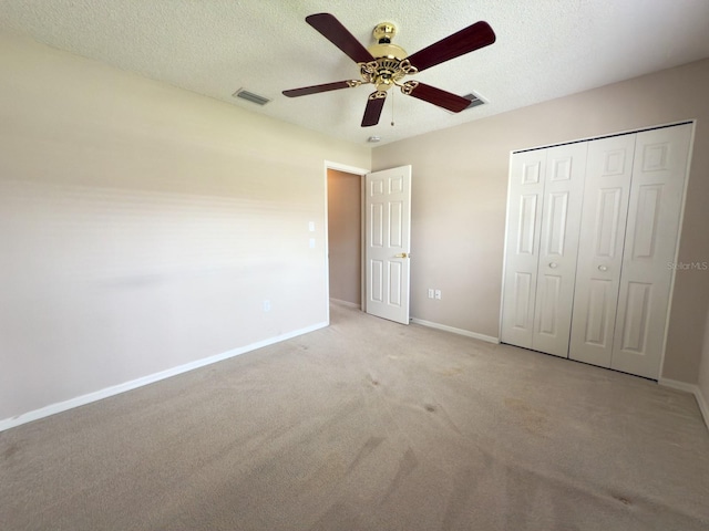 unfurnished bedroom featuring baseboards, carpet, a closet, a textured ceiling, and a ceiling fan